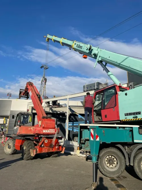 Automacara lângă panouri izolatoare stivuite, la un șantier montan.